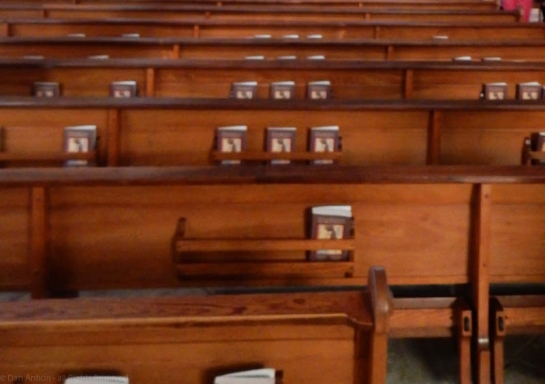 Church pews from back with hymnals, by Dan Antion